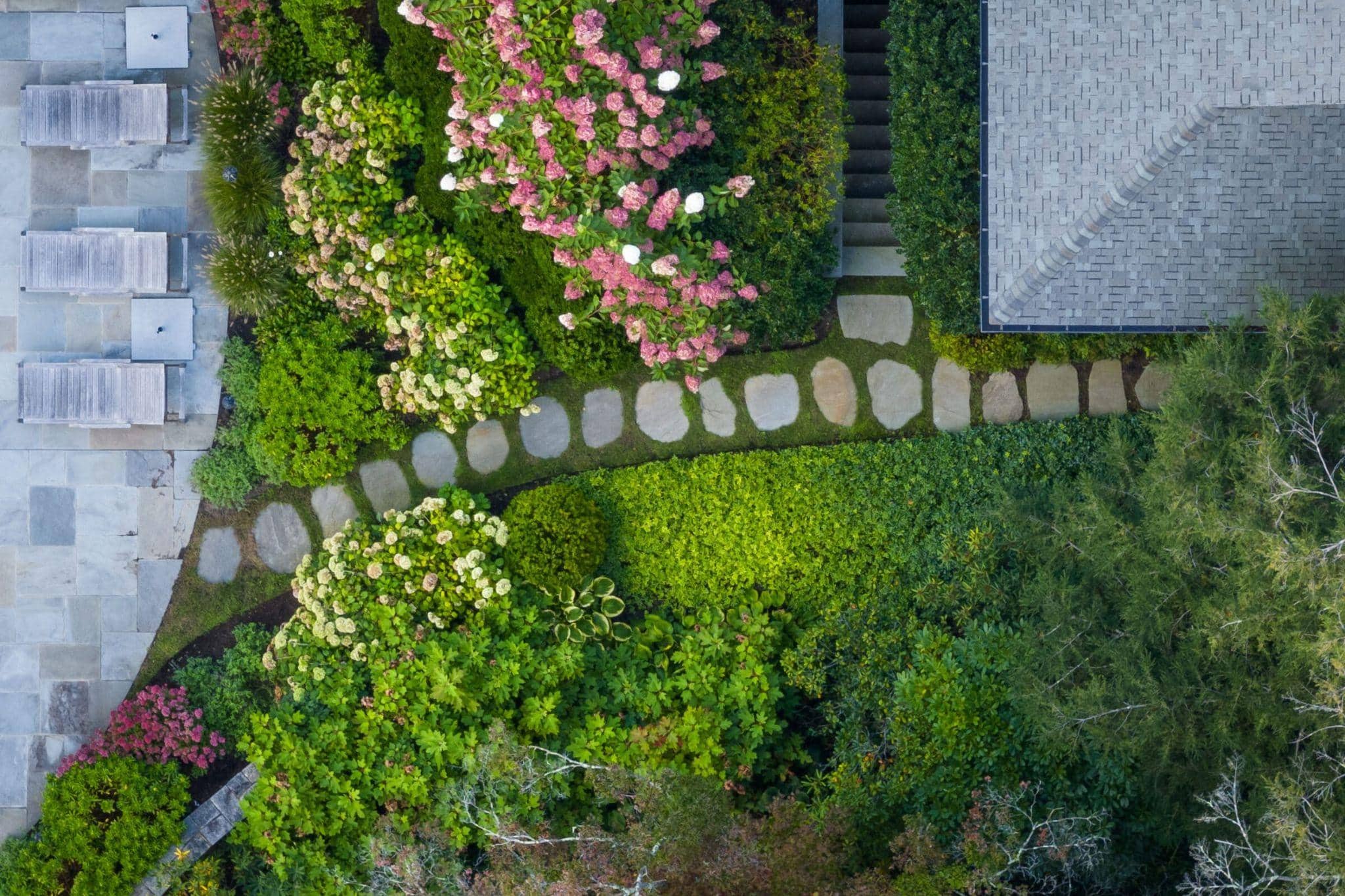Aerial view of stone garden path weaving through layered plantings and lush residential landscape