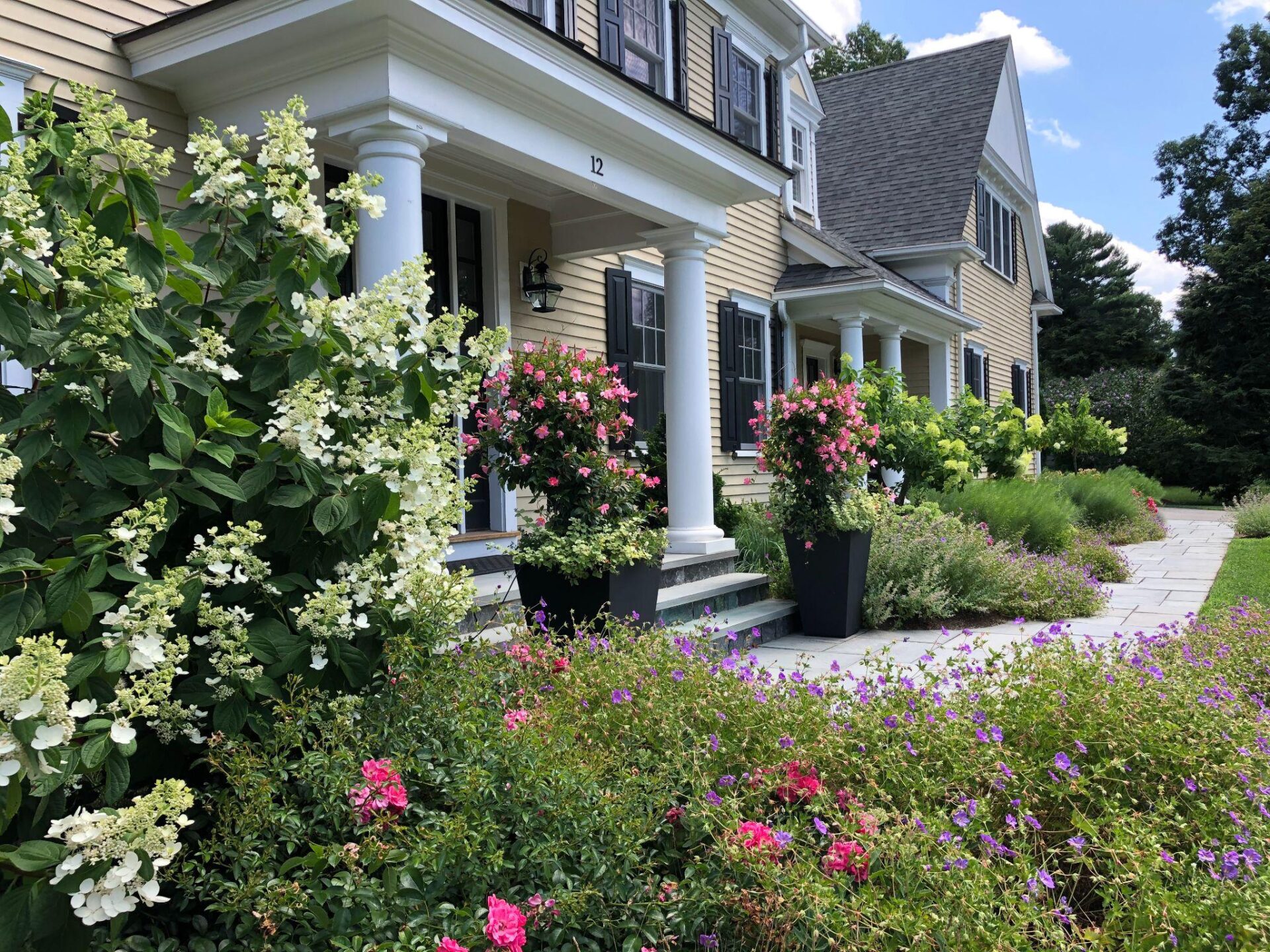 Front garden with flowering shrubs and entry planters at a classic residential home