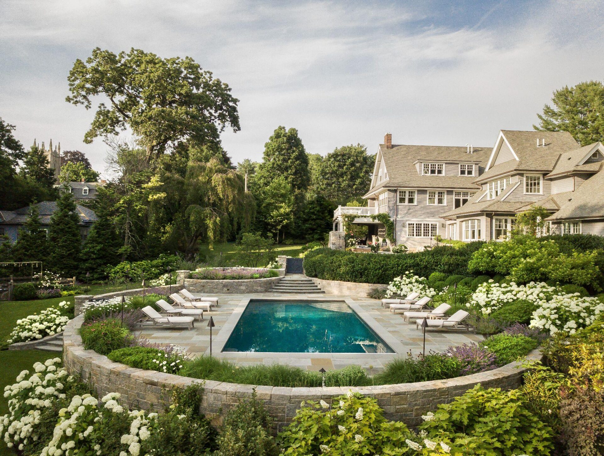Luxury backyard pool surrounded by manicured gardens and mature trees