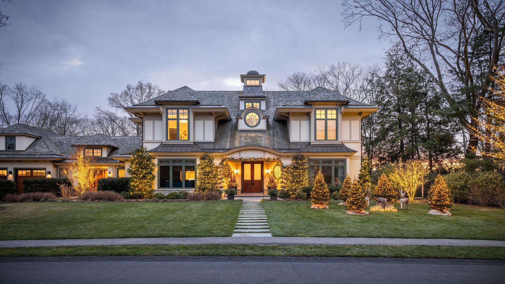 Luxury home exterior with winter landscape lighting and evergreen décor