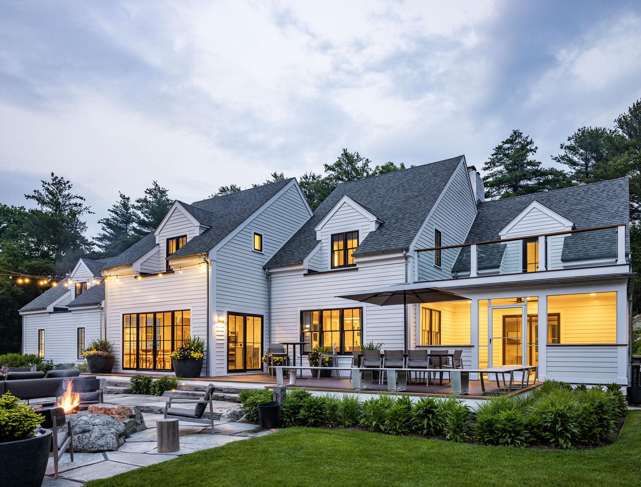 Modern residential outdoor living space with patio, fire feature, and landscape lighting at dusk
