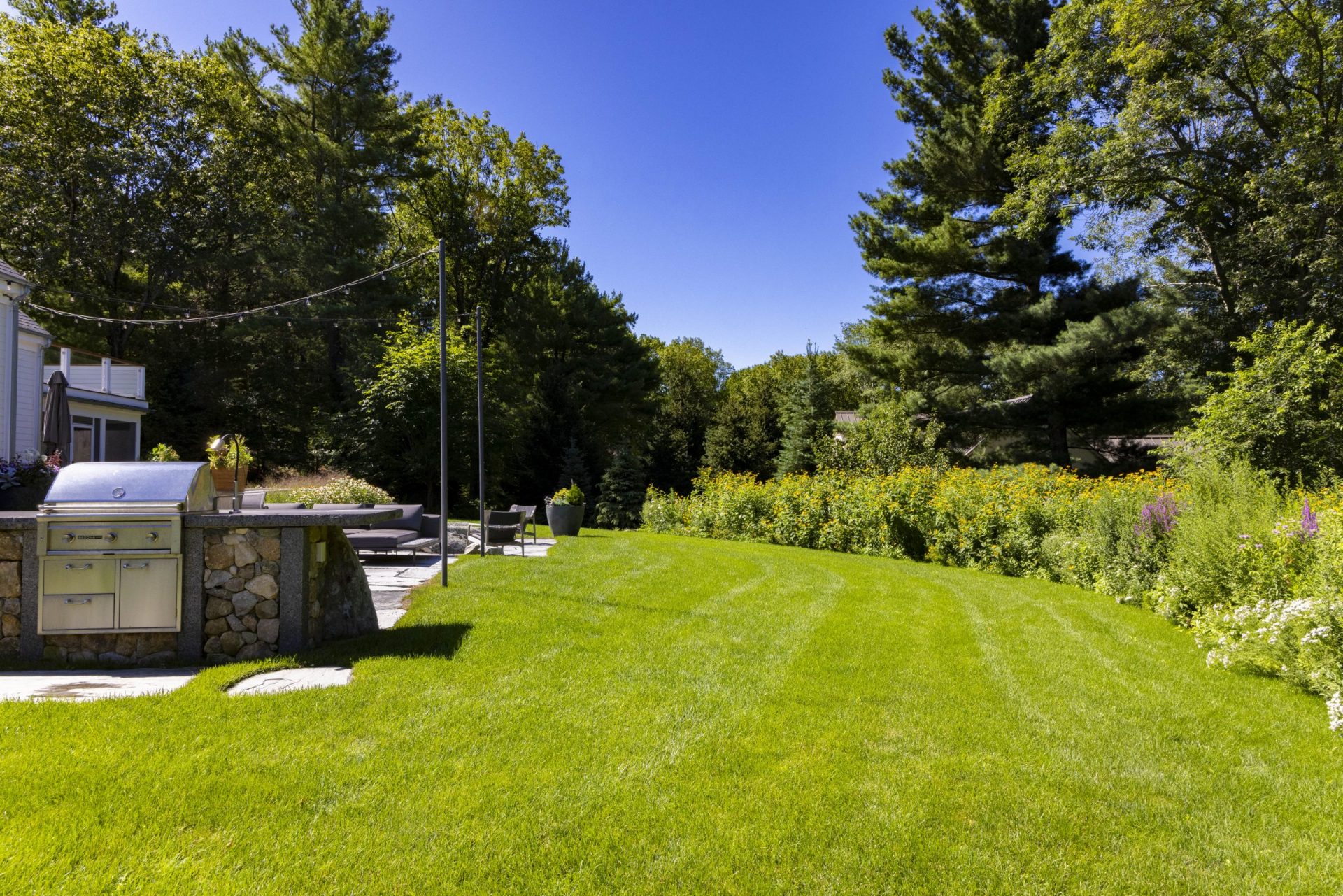 A lush green lawn in a sunny day with an outdoor kitchen setup